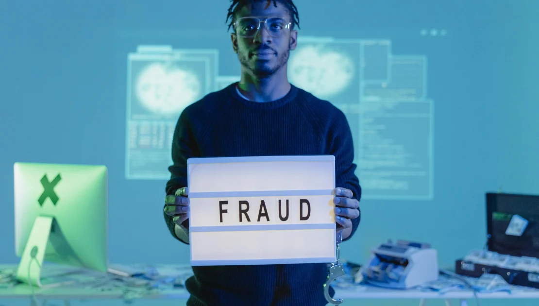 Computer hacker holding 'fraud' sign