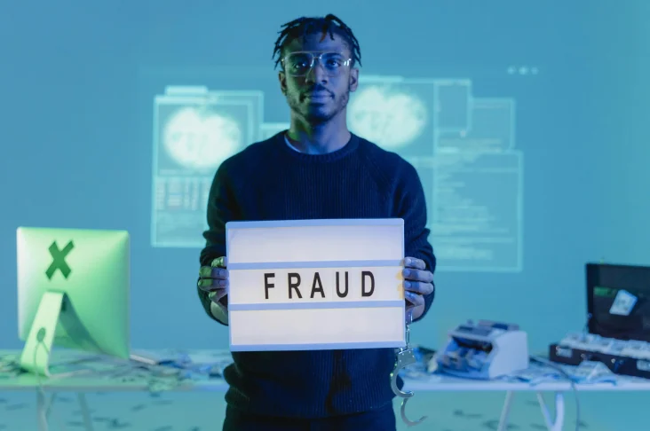 man holding light box with word fraud displayed